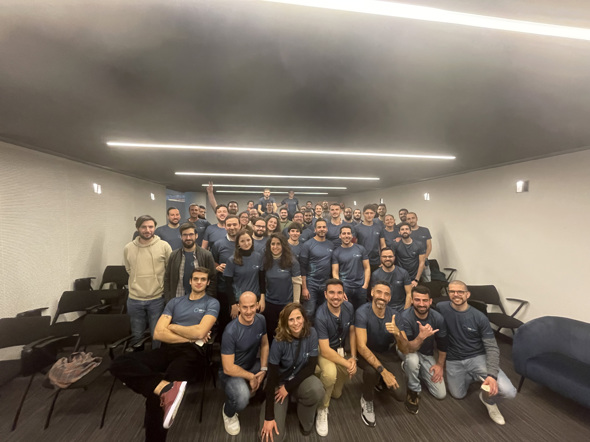 Group photo of the DXspark team, with dozens of smiling team members gathered in a room, wearing company-branded t-shirts. Symbolises DXspark’s sustainable growth and strong team spirit.